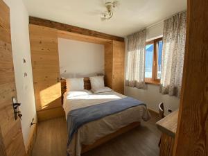a bedroom with a bed in a room with a window at Fra Rose e Mughi in Domegge di Cadore