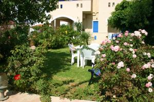a garden with a table and chairs and flowers at Hotel Aglaia in Kalamaki
