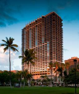 a tall building with palm trees in a park at Trump International Hotel Waikiki in Honolulu