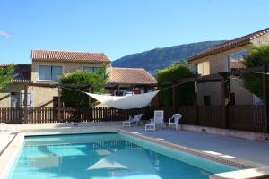 a swimming pool with a hammock and a house at Verdon Vacances in Saint-André-les-Alpes