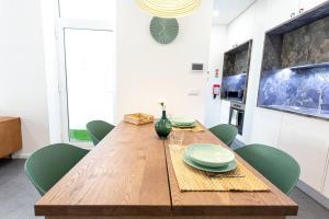 アヴェイロにあるCasa 55の木製のテーブルと緑の椅子のあるダイニングルーム