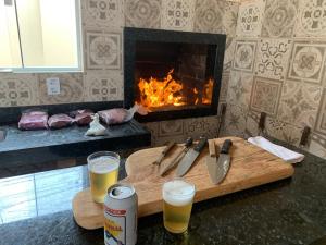 a cutting board with two glasses of beer and a fireplace at Espaço Laranjeira in Campo Grande