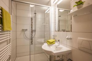 a white bathroom with a sink and a shower at Pension Hinterholzer in Scheffau am Wilden Kaiser