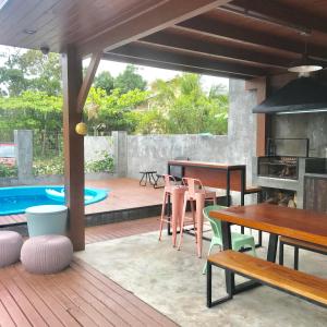 a patio with wooden tables and chairs and a pool at Maná Mariscal Hospedagem in Bombinhas