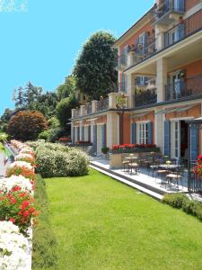 a building with tables and chairs in a yard at Hotel Residence La Luna Nel Porto in Stresa