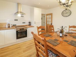 a kitchen and dining room with a wooden table at Hardy Cottage in Benllech