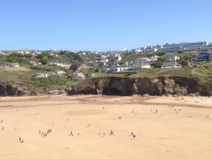 a group of people on a beach with houses at White Ocean in Mawgan Porth