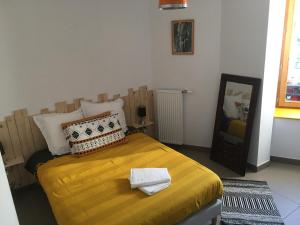 a bedroom with a bed with yellow sheets and a mirror at Les Trois Temps in Saint-Didier-sur-Rochefort