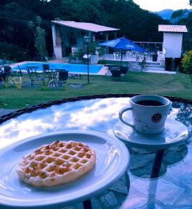 a waffle on a plate next to a cup of coffee at Pousada Village Tere in Teresópolis