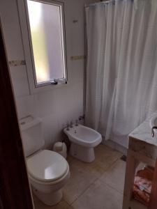 a bathroom with a toilet and a sink and a window at Abril Village in Tandil