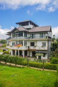 a large white house with a fence in front of it at Suriya Guest in Nuwara Eliya