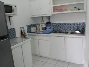 a white kitchen with white cabinets and a microwave at Apartment Espoir in Castries
