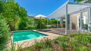 a swimming pool with an umbrella next to a house at Narnia on Thesen Island in Knysna