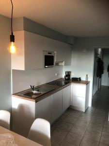 a kitchen with white cabinets and a sink at Residentie Da Vinci Middelkerke in Middelkerke