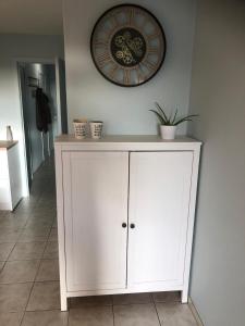 a white cabinet with a clock on the wall at Residentie Da Vinci Middelkerke in Middelkerke