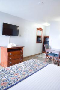 Habitación de hotel con cama, tocador y escritorio. en Knights Inn North Attleboro, en North Attleboro