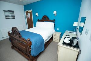 a blue room with a bed with a blue wall at Le Maitre in Southport