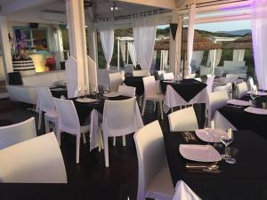 una sala da pranzo con tavoli bianchi e sedie bianche di Baia delle Mimose Garden a Badesi