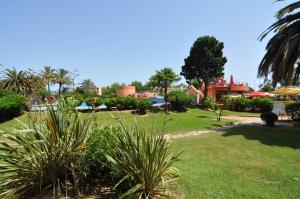 a park with grass and palm trees and buildings at RNET - IR 7-29 Studios Roses Costa Brava in Roses