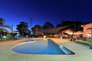 Emu Plains的住宿－比格斯尼皮恩河假日公園，一座游泳池,晚上与大楼相连