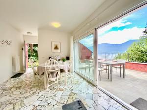 - un salon avec une table, des chaises et une grande fenêtre dans l'établissement Appartamento Buresso, à Porto Valtravaglia