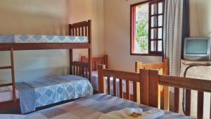 a bedroom with two bunk beds and a tv at Pousada Recantos dos Mineiros in Lençóis