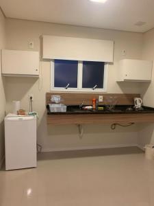 eine Küche mit einem weißen Kühlschrank und einem Fenster in der Unterkunft Apto Top Centrum Holambra/excelente localização in Holambra