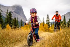 a little girl riding a bike on a dirt road at Blackstone Mountain Lodge by CLIQUE in Canmore