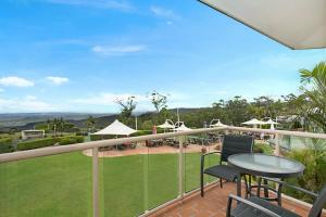 einen Balkon mit einem Tisch und Stühlen sowie einem Grasfeld in der Unterkunft Eagle Heights Mountain Resort in Eagle Heights