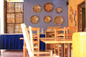 Tripui Hotel في Puerto Escondido: غرفة طعام مع طاولة وكراسي وأطباق على الحائط