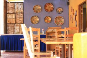 une salle à manger avec une table, des chaises et des assiettes murales dans l'établissement Tripui Hotel, à Puerto Escondido