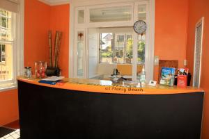 an orange kitchen with a counter with a clock on the wall at Manly Bunkhouse in Sydney