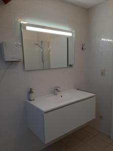 a white bathroom with a sink and a mirror at Huis Pimpernel in Bredene +25 photos
