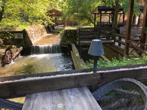 a wooden bench sitting in front of a waterfall at Garni hotel Vir in Vrnjačka Banja