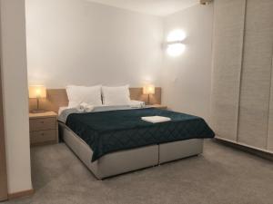 a bedroom with a bed with a green comforter at Garni hotel Vir in Vrnjačka Banja