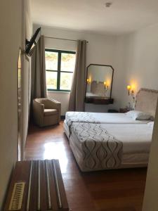 a bedroom with a bed and a chair and a mirror at Hotel Castelo de Vide in Castelo de Vide +40 photos