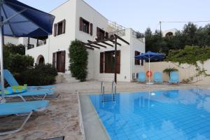 a pool with chairs and umbrellas in front of a house at dreamvillas-crete - villa Helios - villa Thalassa in Almirida