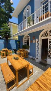 un patio avec des tables en bois et un bâtiment bleu dans l'établissement Angatu Hostel, à São Paulo