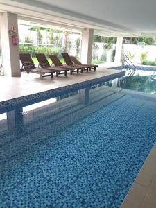 a swimming pool with benches sitting next to a pool at Flat Vip 5 Estrelas Granja Vianna Moderno Sofisticado Alto Padrão Animália Park! in Cotia