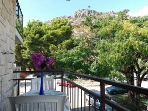a vase of purple flowers sitting on a balcony at Dvokrevetna soba s balkonom i kuhinjom in Podgora