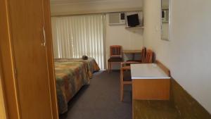 a hotel room with a bed and a table and a desk at Collie Motel in Collie