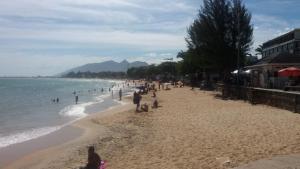 a group of people on a beach near the water at Pousada Bartrô in Rio das Ostras