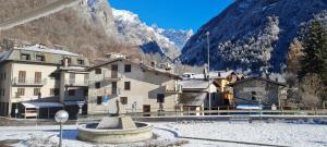 a town with buildings and a fountain in front of a mountain at Hotel ristorante Bucaneve in Val Masino
