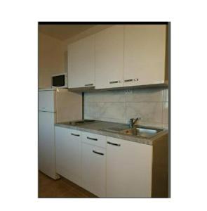 a white kitchen with a sink and a refrigerator at Apartmani Kelava in Podgora