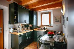 a kitchen with dark green cabinets and a table with a tableablish at The Cozy Nest - Bellano in Bellano