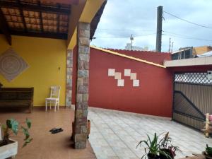 a patio of a house with a red and yellow wall at Hospedaria Namastê in Peruíbe
