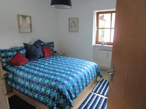 Schlafzimmer mit einem Bett mit blauen und roten Kissen in der Unterkunft Hammerhaus-Apartment 3 in Siegsdorf