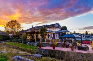 a large house with a sunset in the background at Birds of a Feather Victoria Oceanfront Studio Suites in Colwood