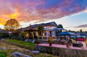 a large house with a sunset in the background at Birds of a Feather Ocean Lagoon Victoria Condos in Colwood