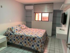 a small bedroom with a bed and a television at Apartamento amplo com acesso direto à praia! in Cabedelo +11 photos